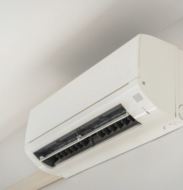 A modern white ductless mini-split heatpump unit mounted on a light-colored wall near the ceiling.